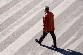 老人就走在空荡荡的大街上使用高的人行横道的影子