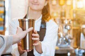 咖啡师用可重复使用的不锈钢杯递上咖啡