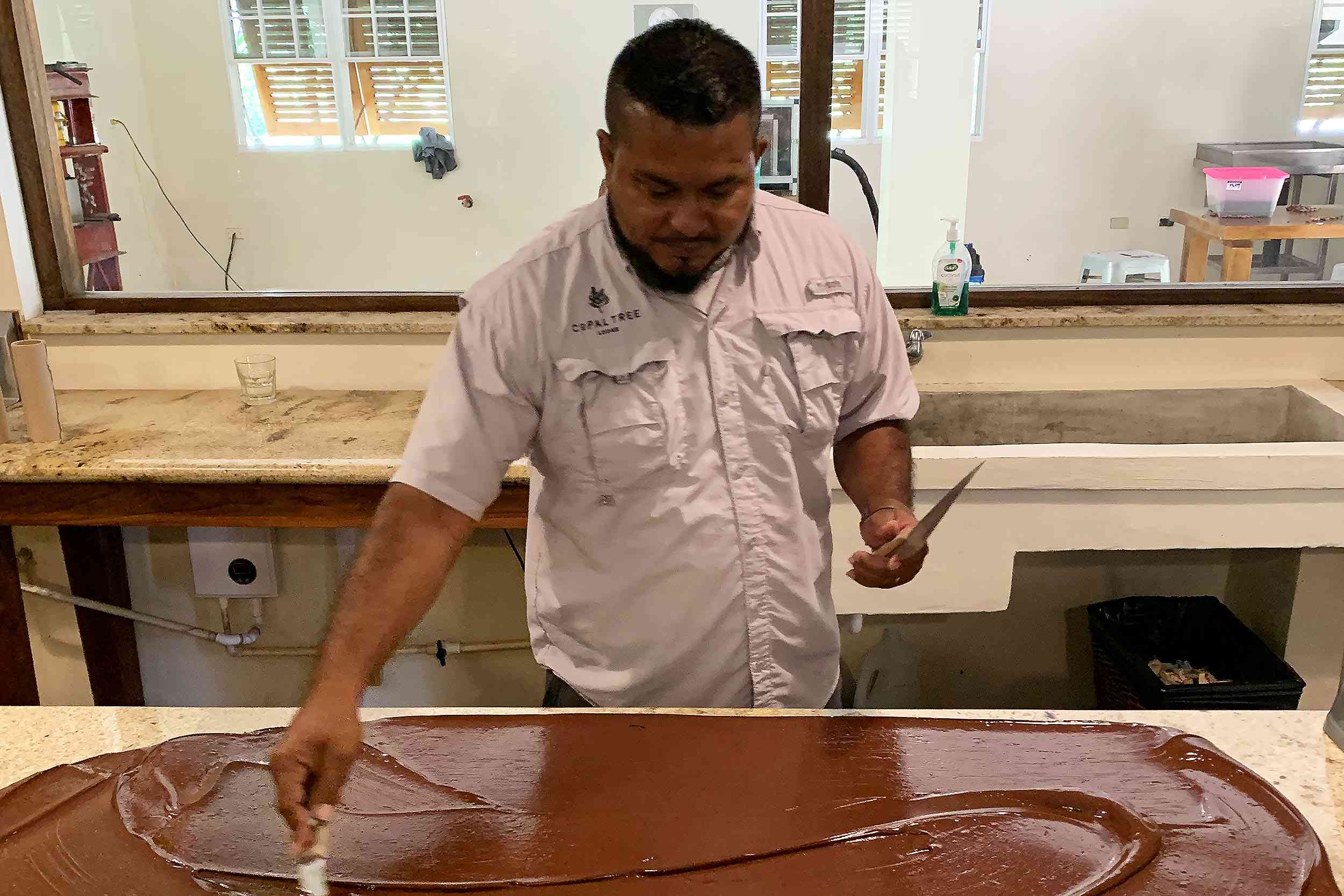 伯利兹工厂，一名男子在大理石板上调和巧克力＂width=