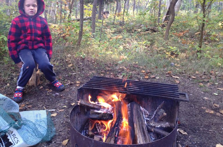 在树林里，一个小孩坐在火炉前的水壶里