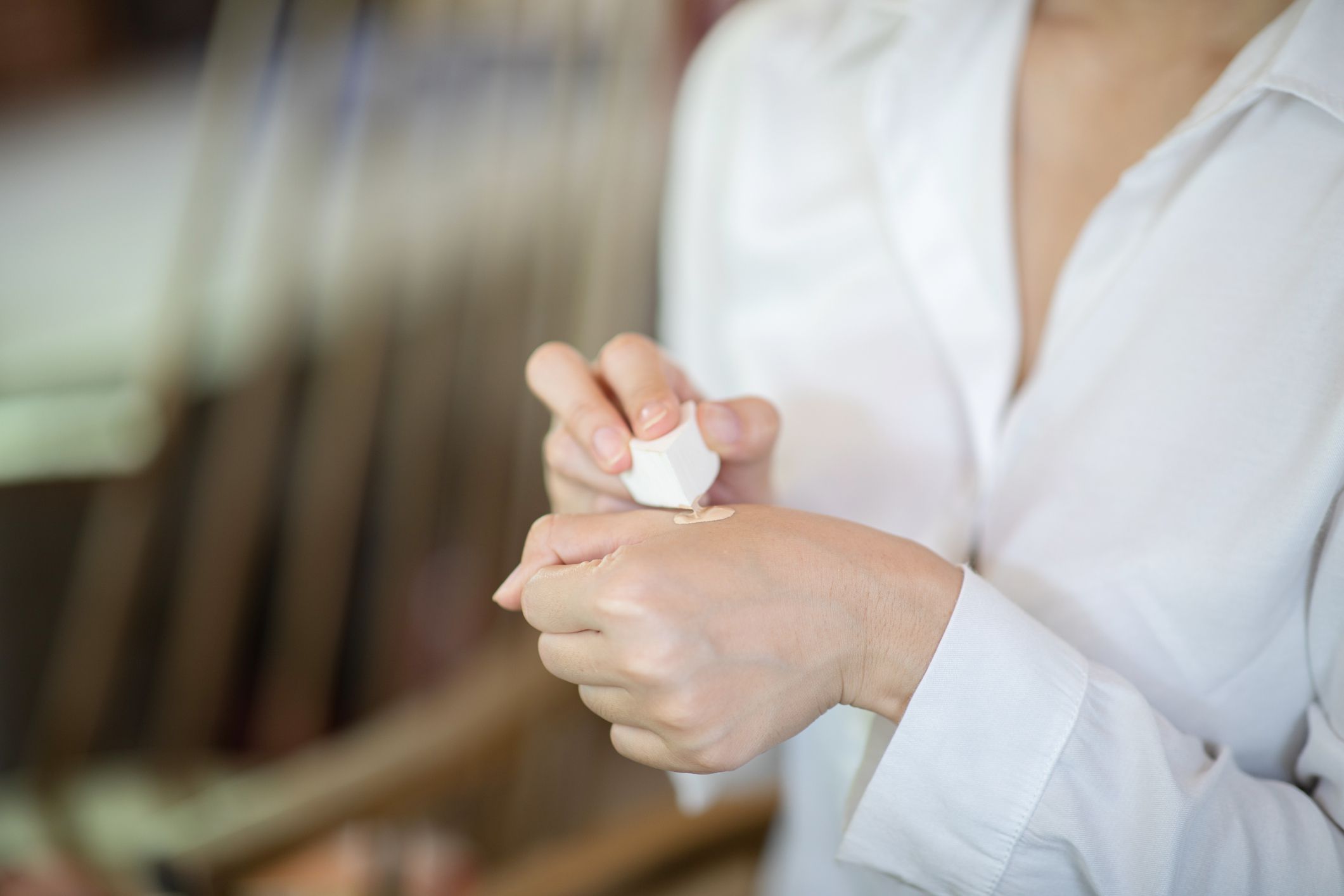 一名身穿白衬衫的女子用手上的海绵给粉底加热。