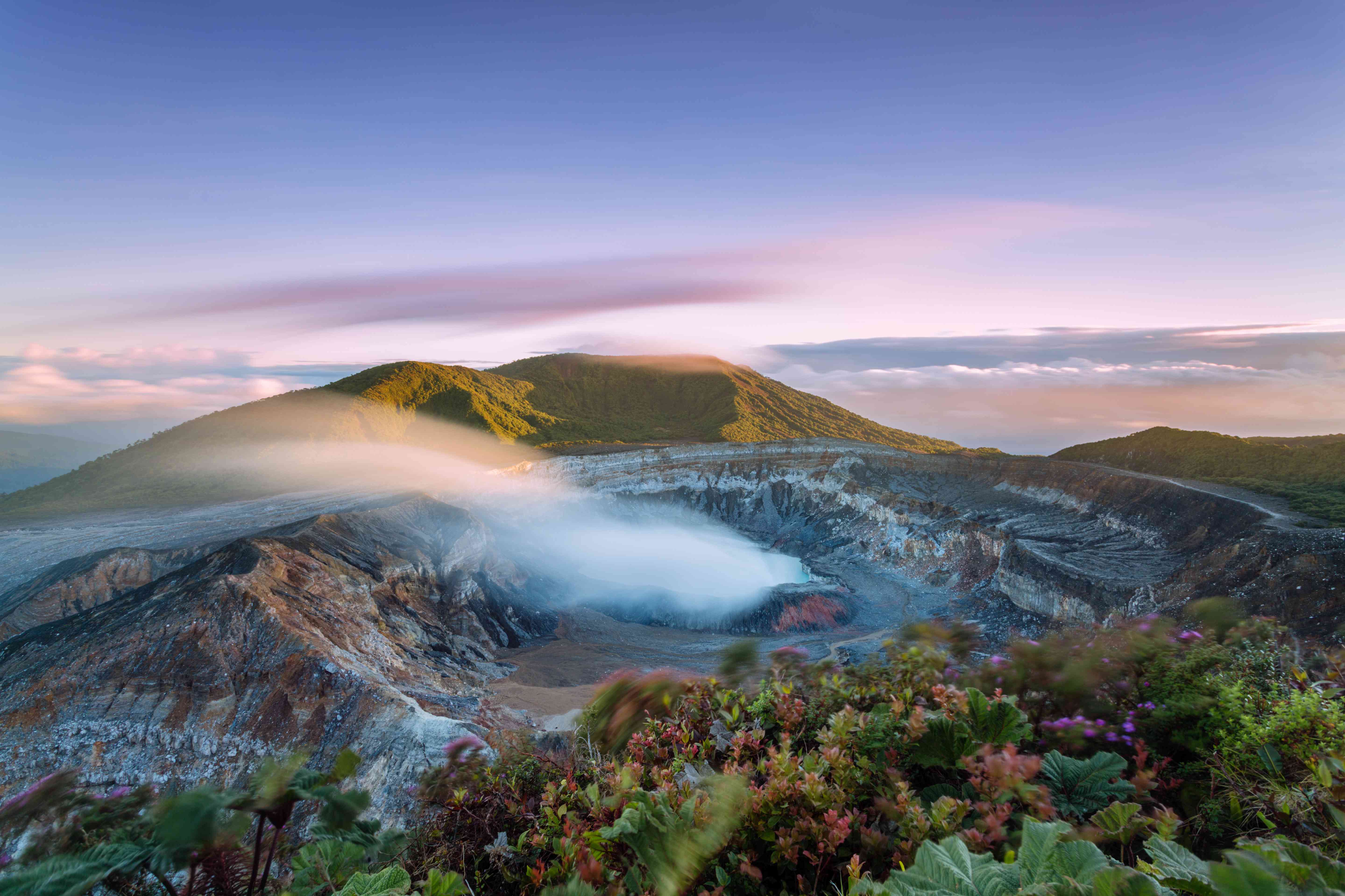 日落时分，哥斯达黎加火山口冒出的浓烟＂width=