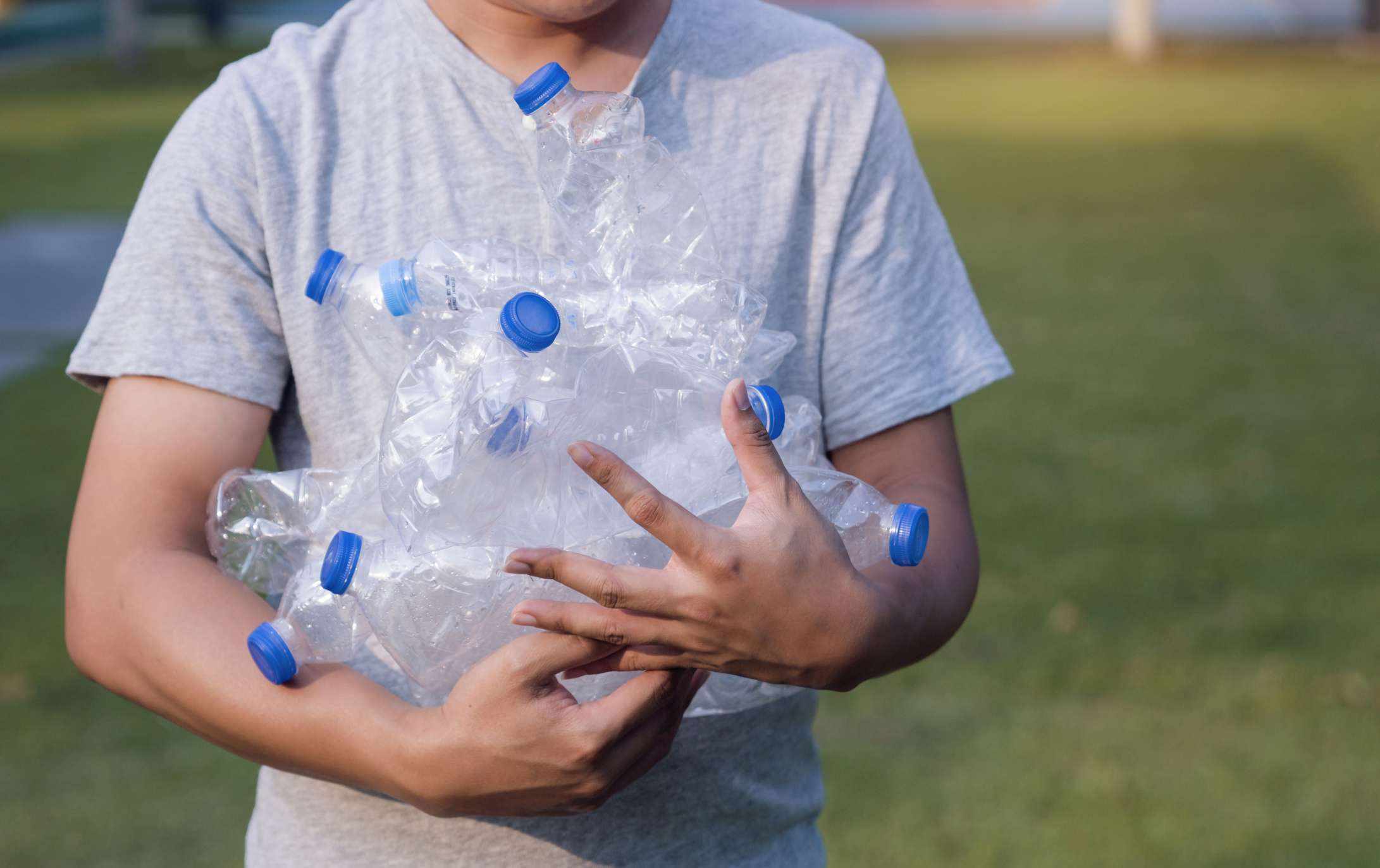 一位年轻女子在公园里回收塑料瓶。