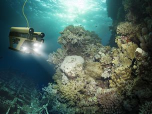 一个带着前灯探索水下礁石的机器人。一根绳子挂在机器人身上。