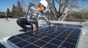 女建筑工人在住宅屋顶上安装太阳能电池板。