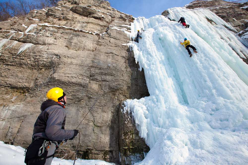 登山者在陡峭的岩层上攀登结冰的瀑布