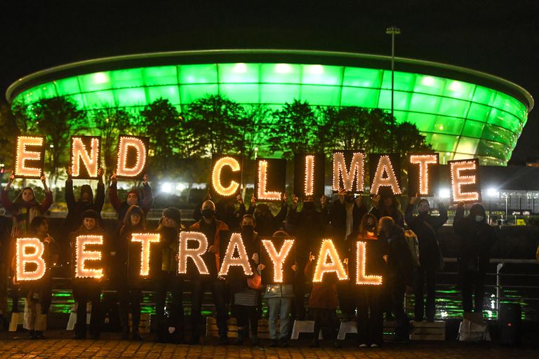 COP26会议在夜间举行抗议活动。抗议者举着一个牌子，上面写着“结束气候背叛”。