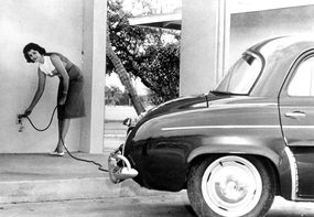 一名妇女收取电动汽车“ Henney Kilowatt”的景象。“width=