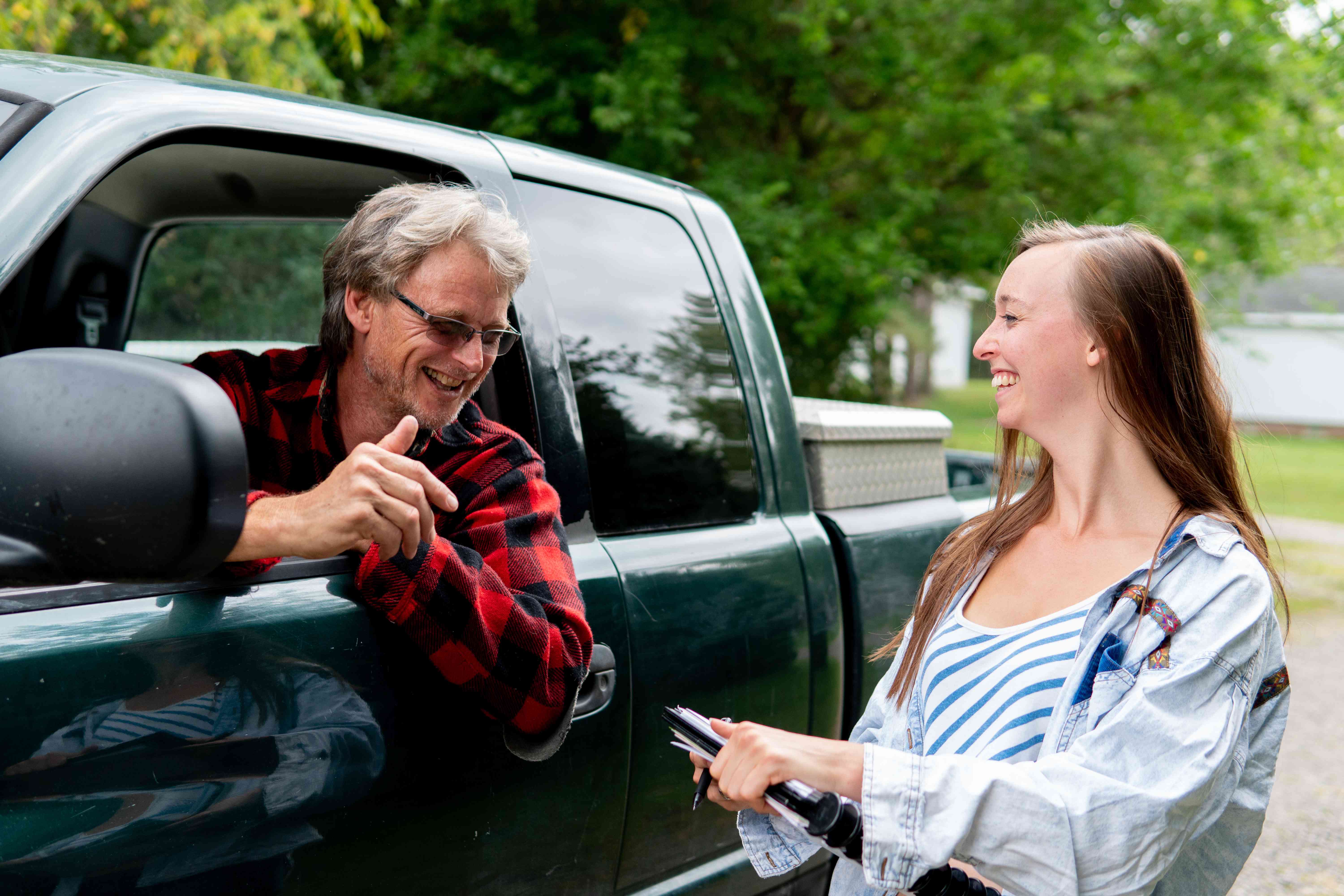 卡车里的老男人探出车窗和拿着写字板的年轻女人说话