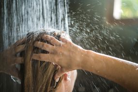 一个女人在带有自然光线的浴室里洗头发。