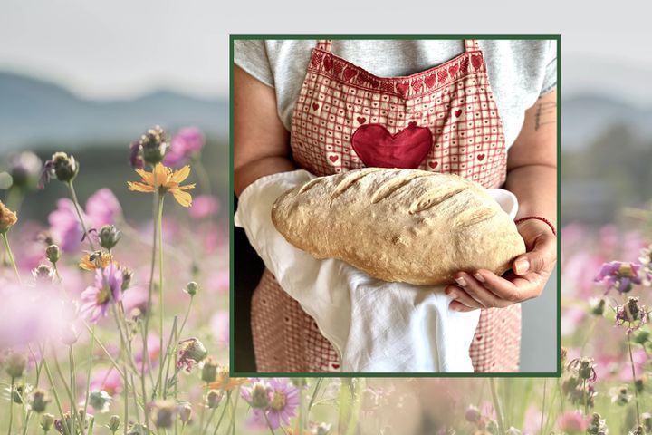 A person holds fresh bread in a tea towel