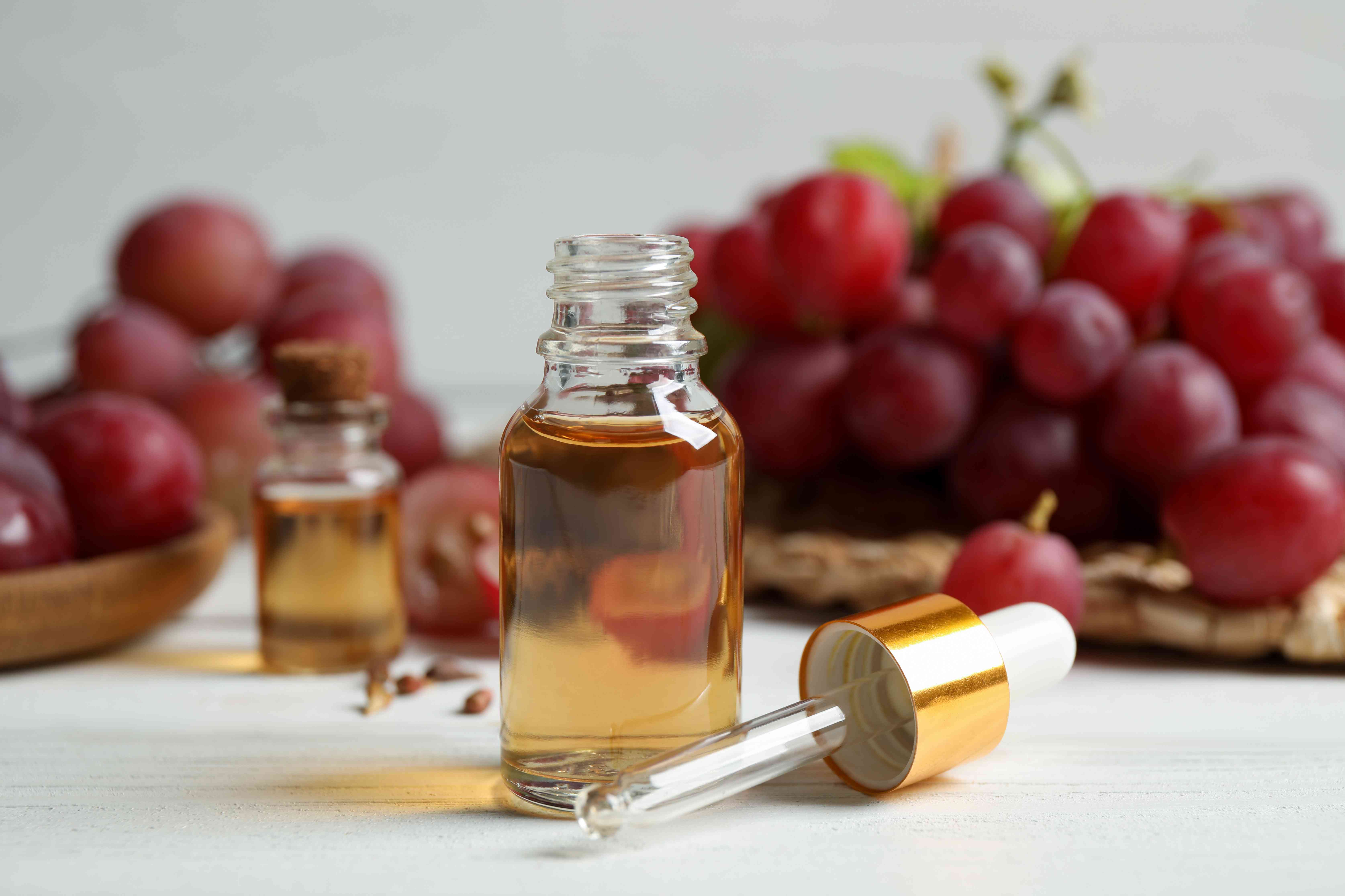 一瓶天然葡萄籽油放在白色木桌上。有机化妆品