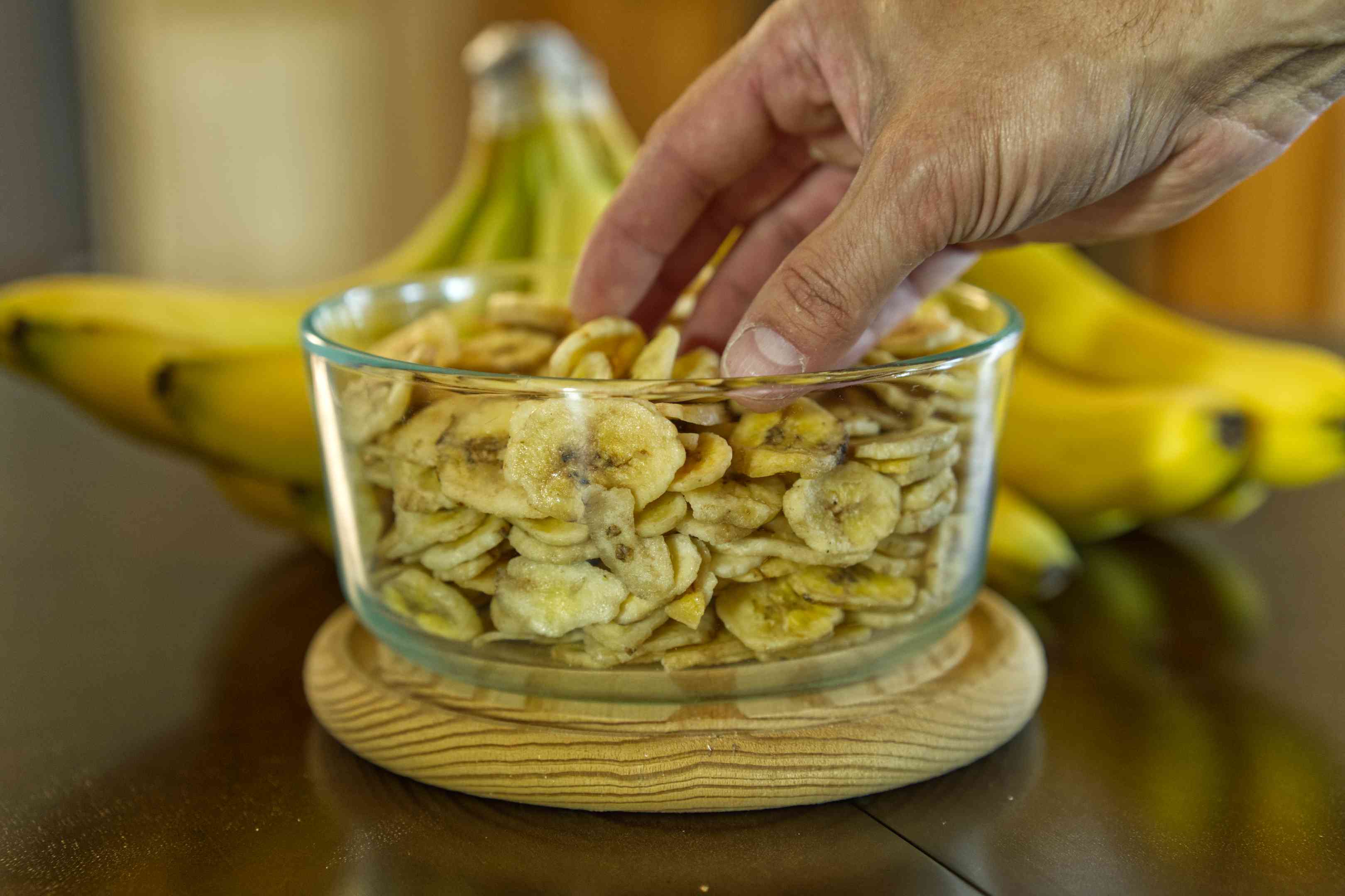 把手伸进盛有干香蕉片的玻璃罐中，放在桌上