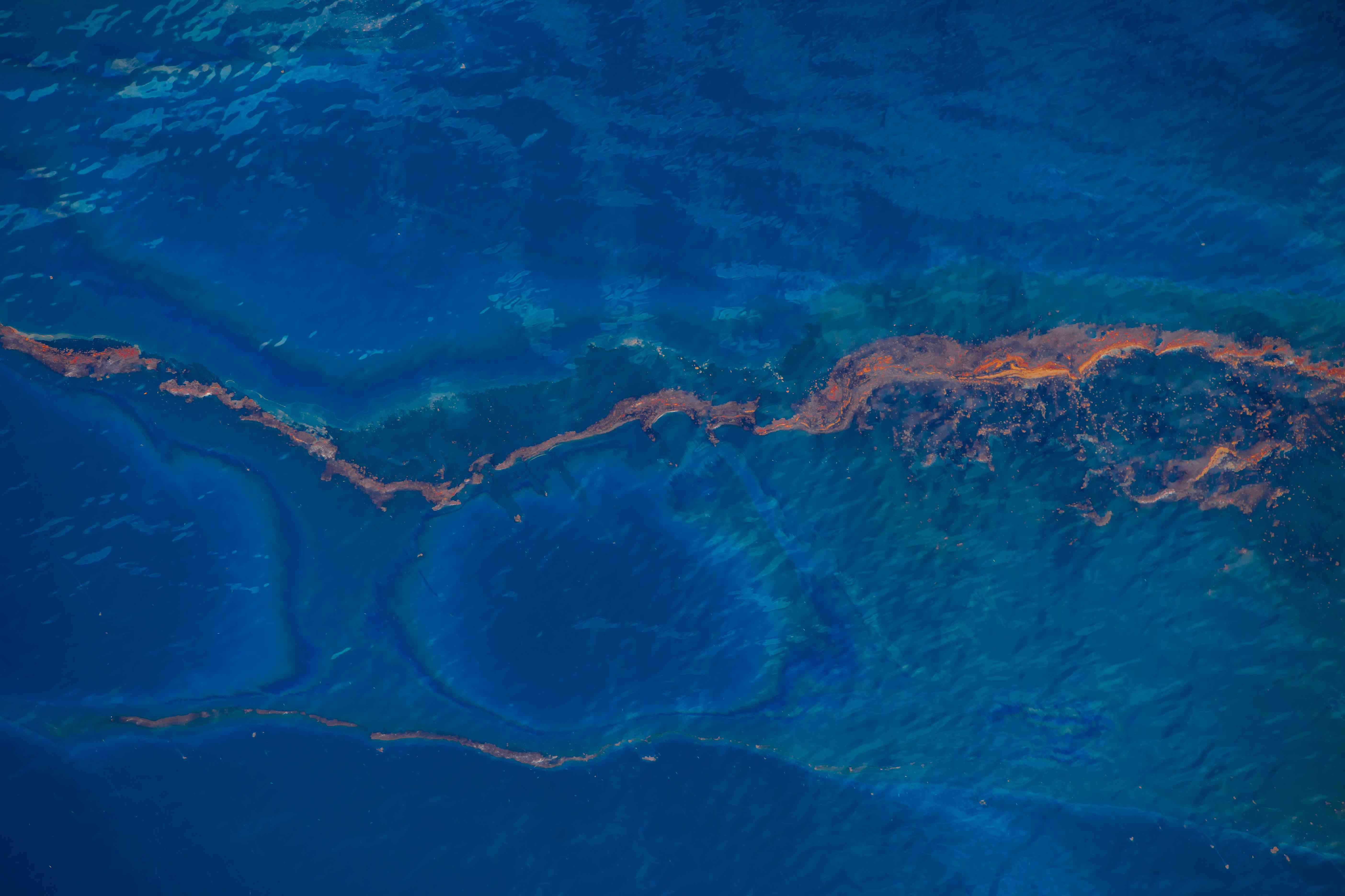 棕色原油聚集在海洋表面＂width=