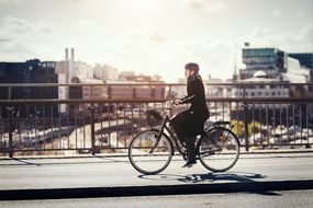 女人在城市骑自行车“width=