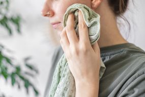 女人使用绿色毛巾和自制的DIY卸妆液来清洁脸部“width=