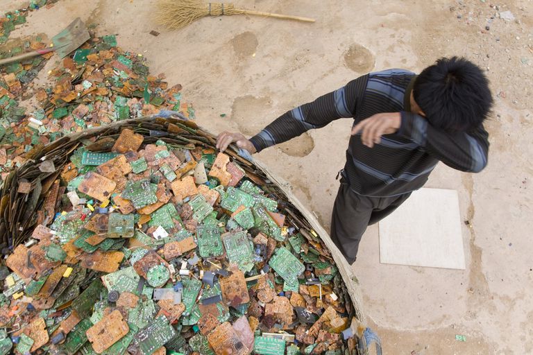 在中国，一名男子捂着脸在电子垃圾中分类。