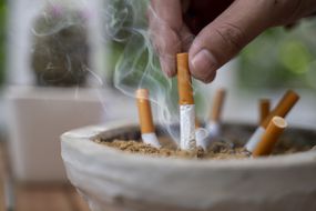 关闭男人的人熄灭烟灰盘中的香烟，戒烟没有吸烟肺部健康问题