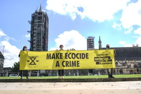 8月28日，在英国伦敦议会广场，人们举着写有“生态灭绝是一种犯罪”的横幅。