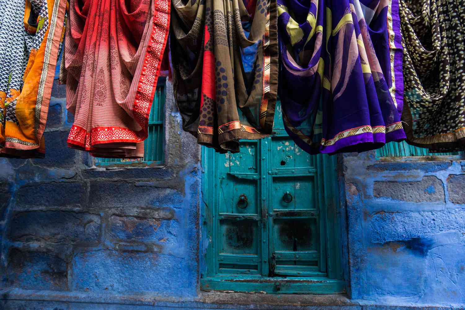 在印度，纱丽挂在蓝色的墙上＂width=