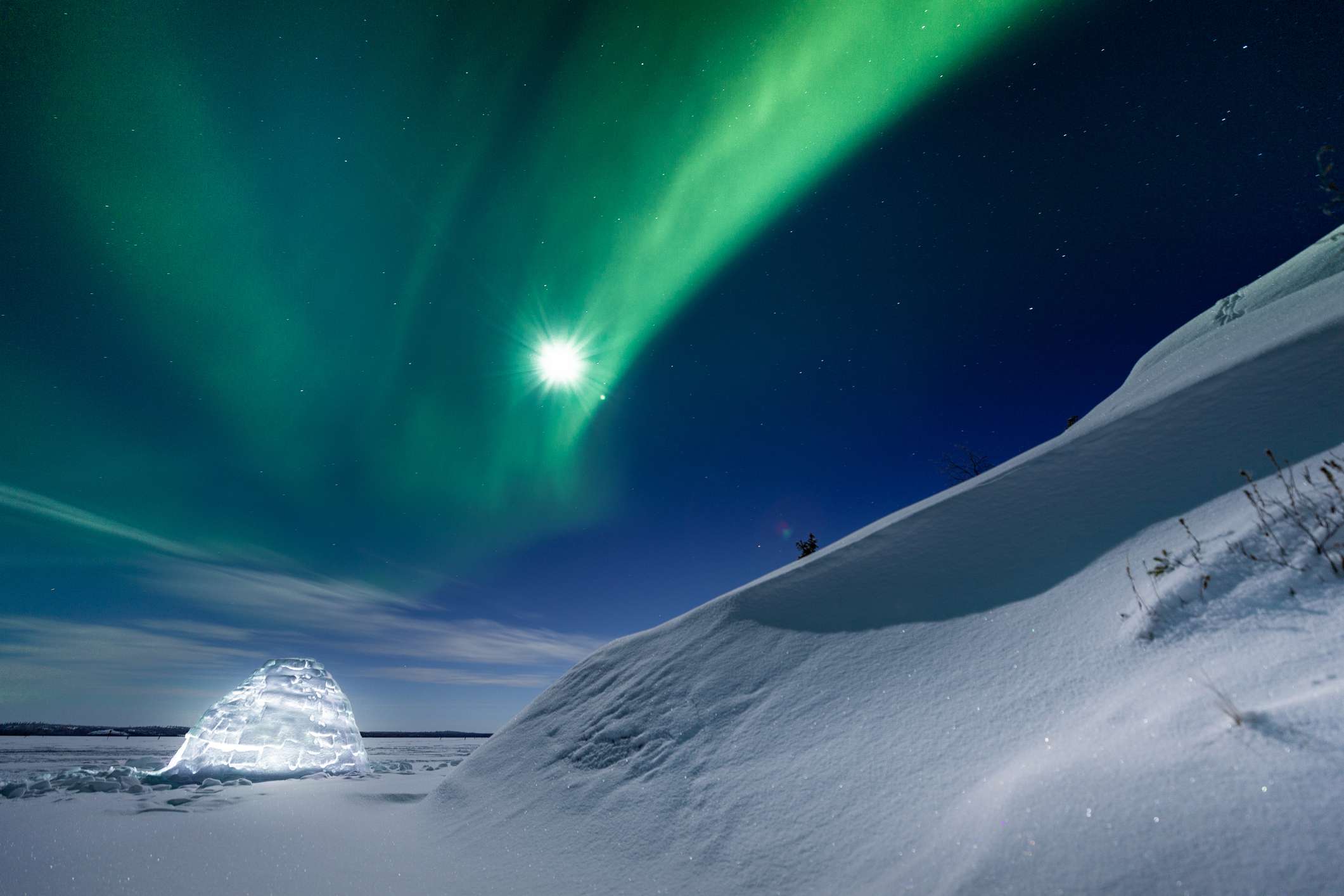 在北极光下发光的冰屋和冰雪覆盖的景观