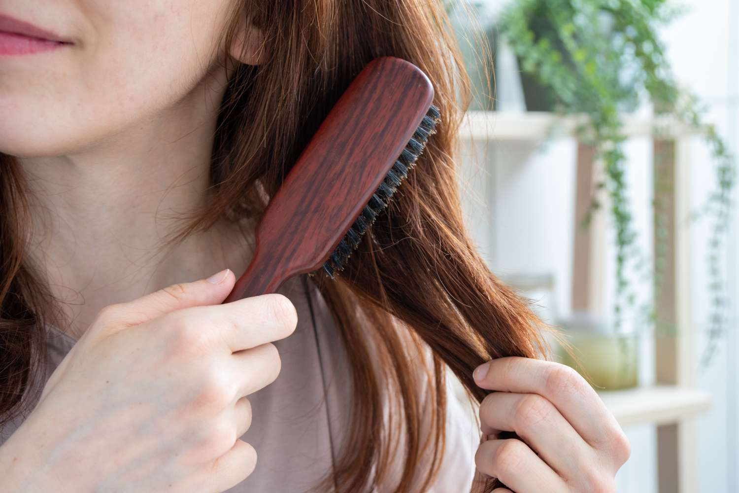女性用天然木刷和鬃毛梳理长发的特写镜头