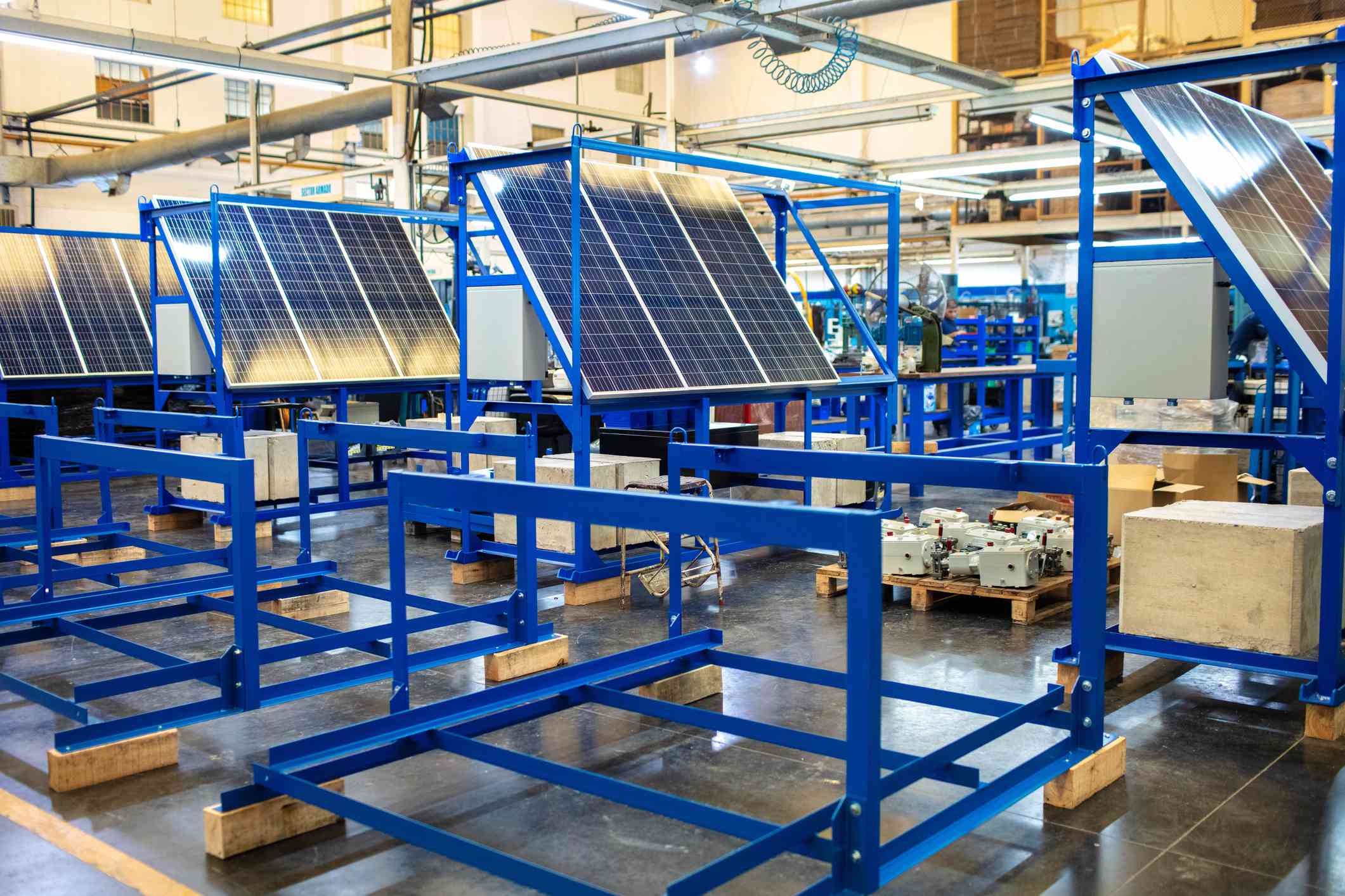 工业仓库的内部，太阳能电池板被抬高在位于车间的展台上。＂width=