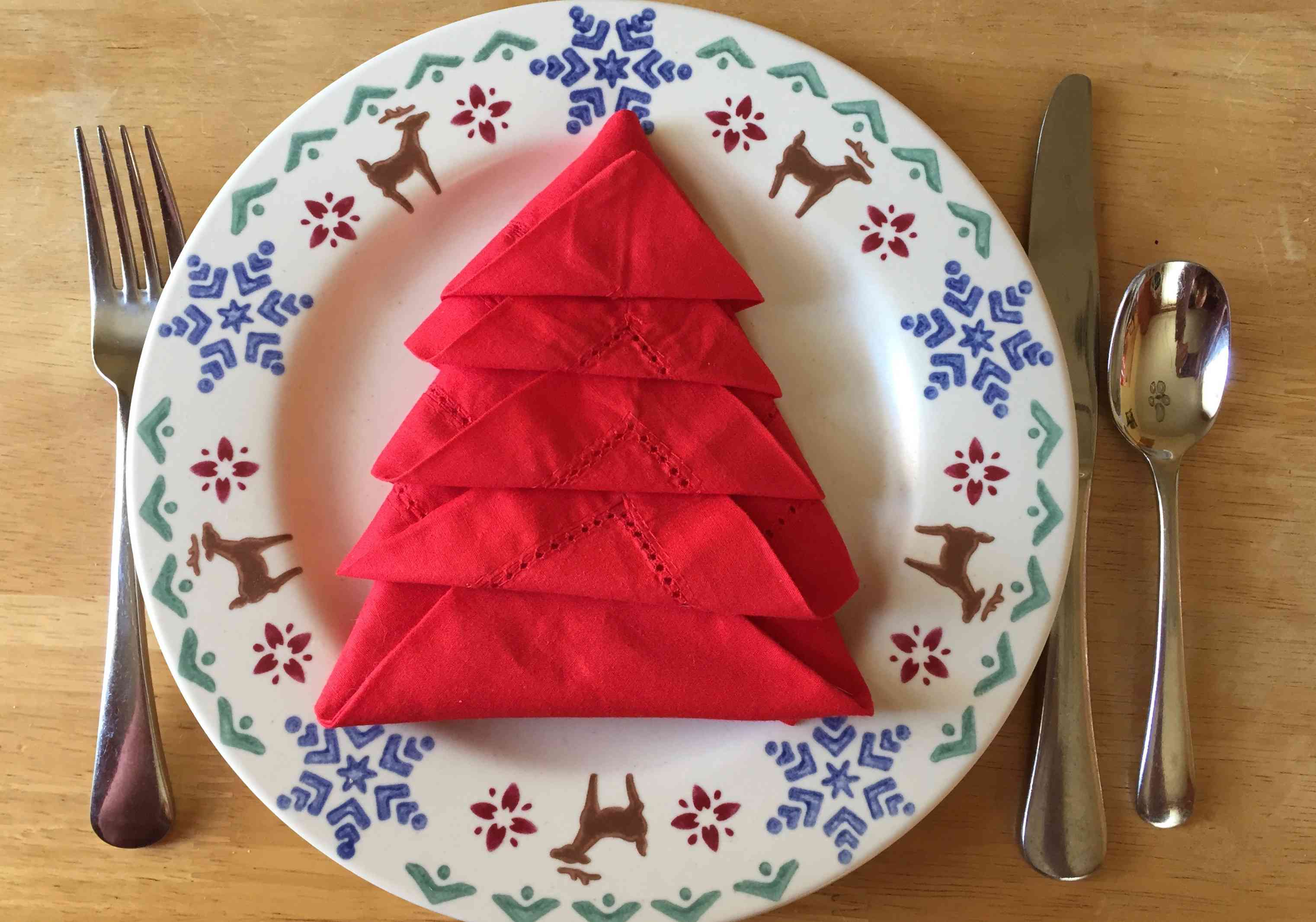 红色的餐巾折叠成驯鹿板上的圣诞树