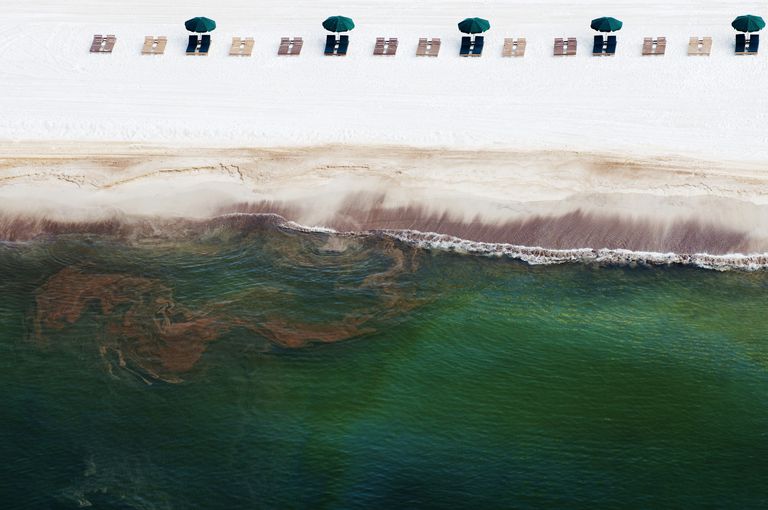 当石油冲上岸时，空的沙滩椅躺在沙滩上