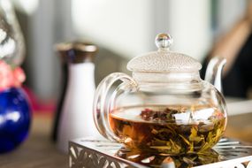 玻璃茶壶装满热水和新鲜的草药，从花园制作草药茶