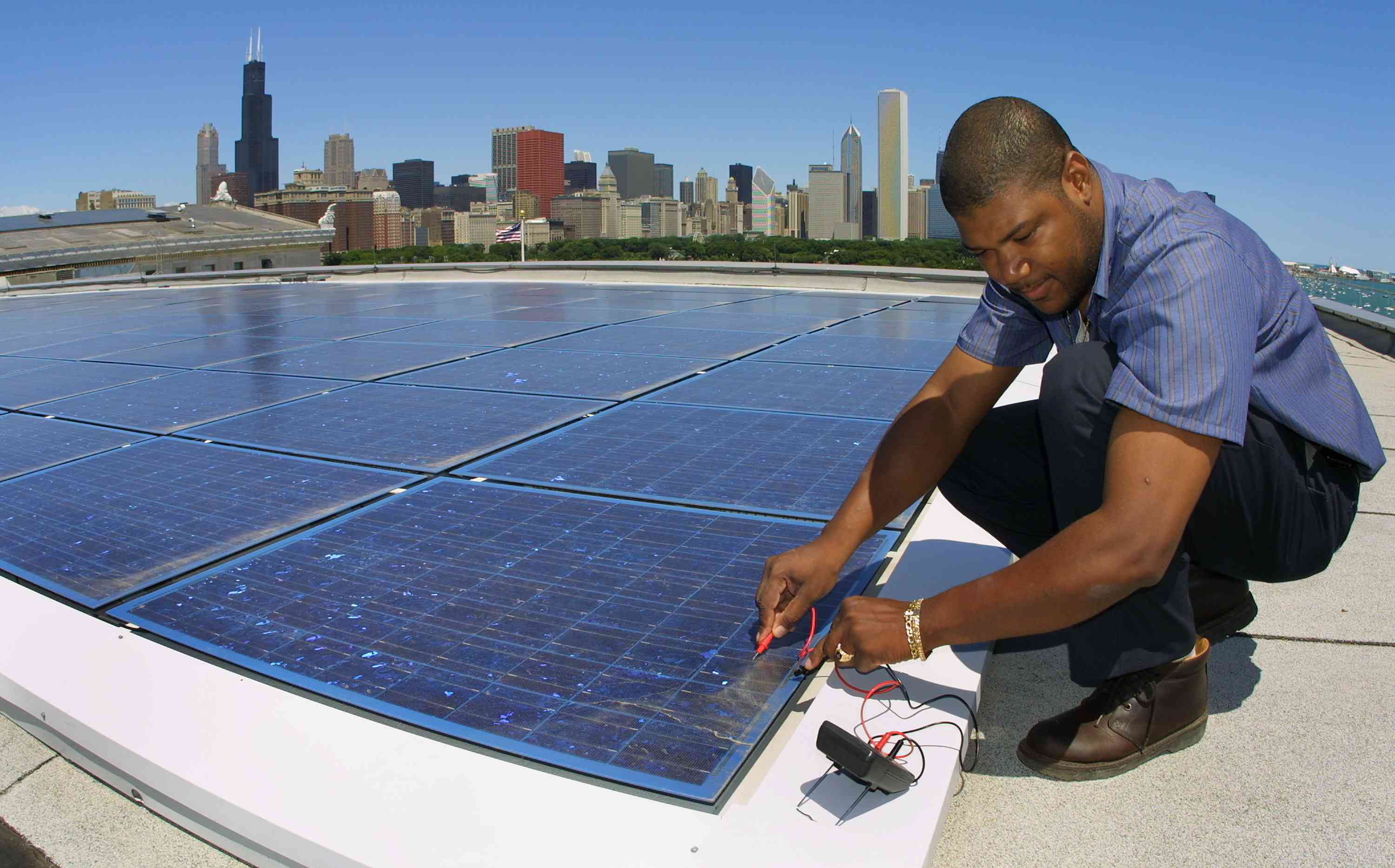 建筑工程师Ernst Loubeau在2001年7月5日在芝加哥野外自然历史博物馆屋顶上的太阳能电气系统执行诊断维护程序。“width=