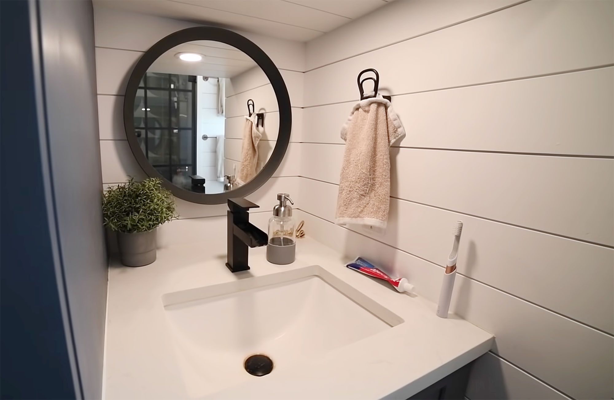 Sydne Gold设计的一个小房子的内部，展示了浴室水槽和镜子。