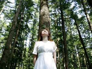 森林里靠在树上的年轻女子