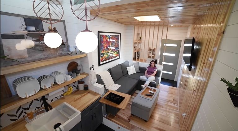 由Sydne Gold设计的一个小房子的内部图像，展示了厨房、起居室和坐在沙发上的Gold。