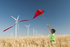 一个小男孩在一个装有风力涡轮机的地方放风筝。