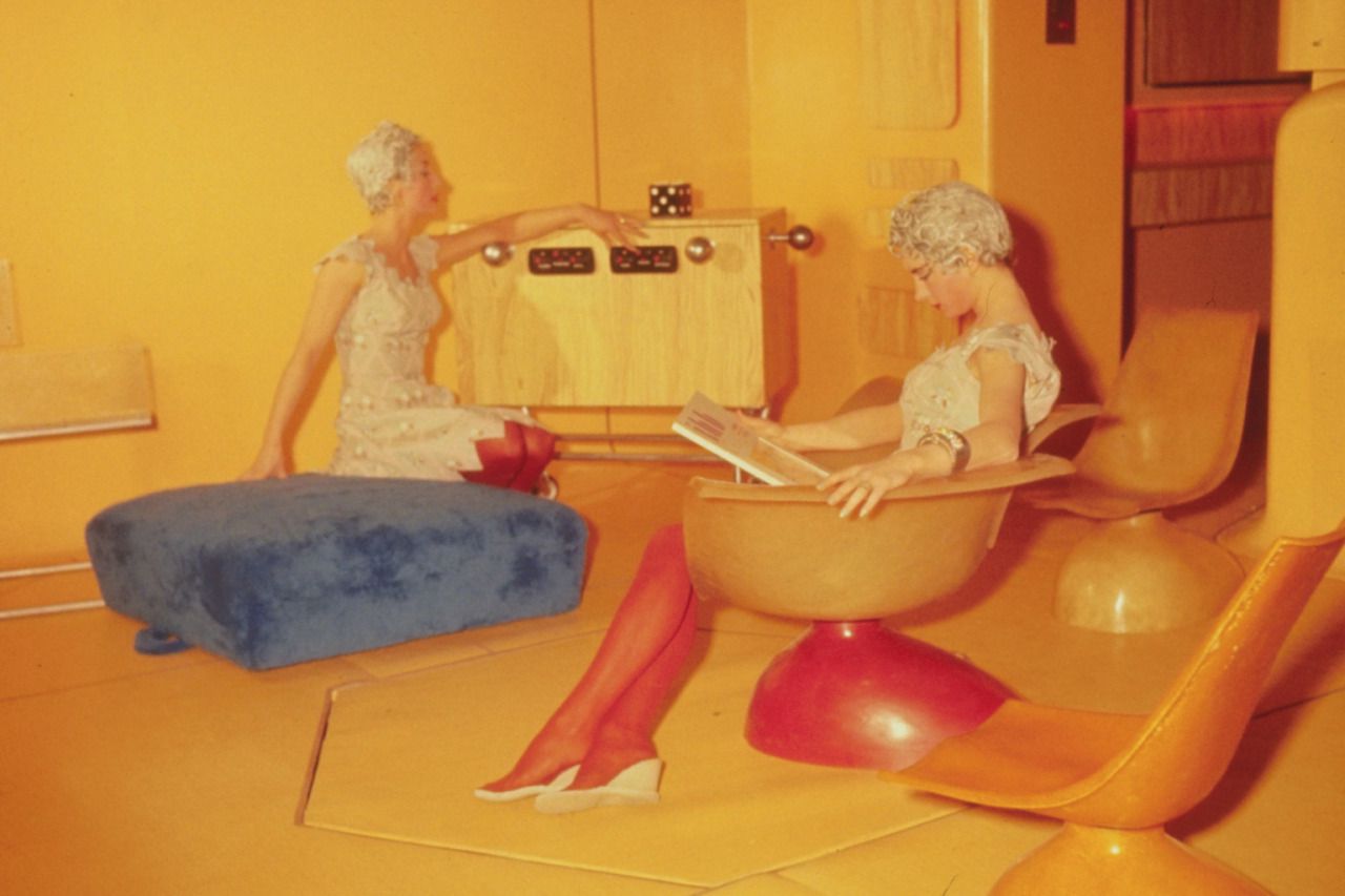 两个女人坐在一个黄色的未来派客厅里