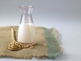 豆浆的特写镜头，在白色背景下粗麻袋上的大豆