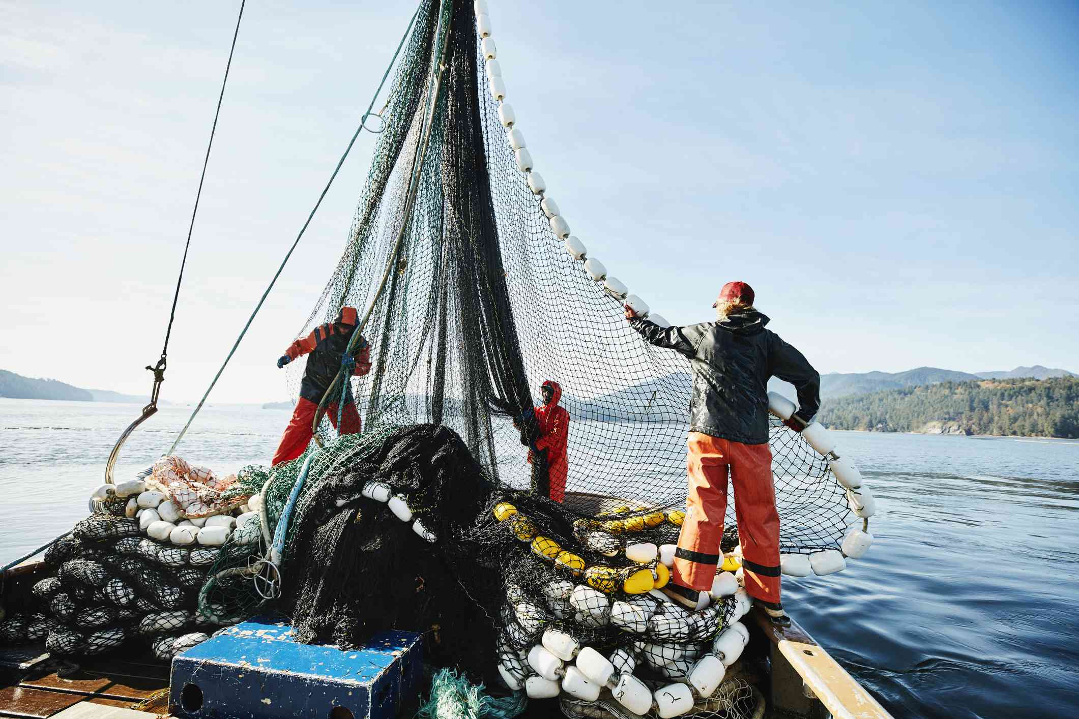 在商业渔船上操纵渔网的渔民。