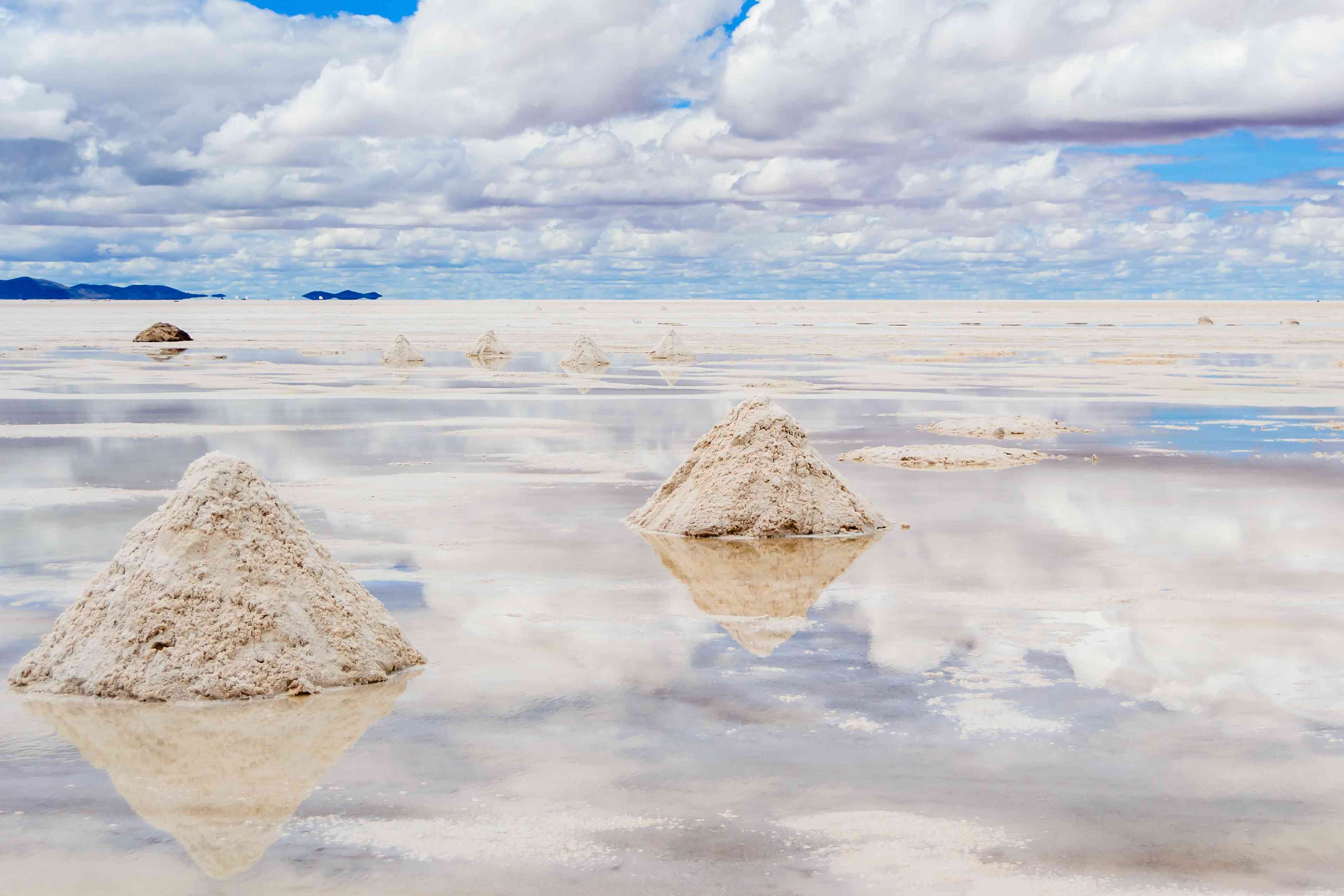 乌尤尼盐沼中反射的三角形盐堆和云
