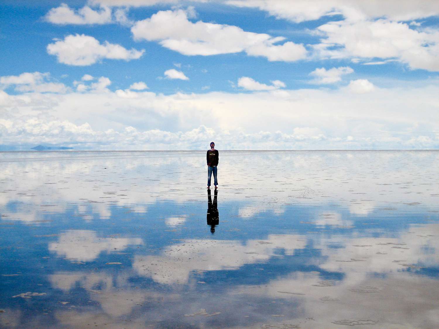 男人望向天空,而天空站在乌龙尼盐湖而反映在地上