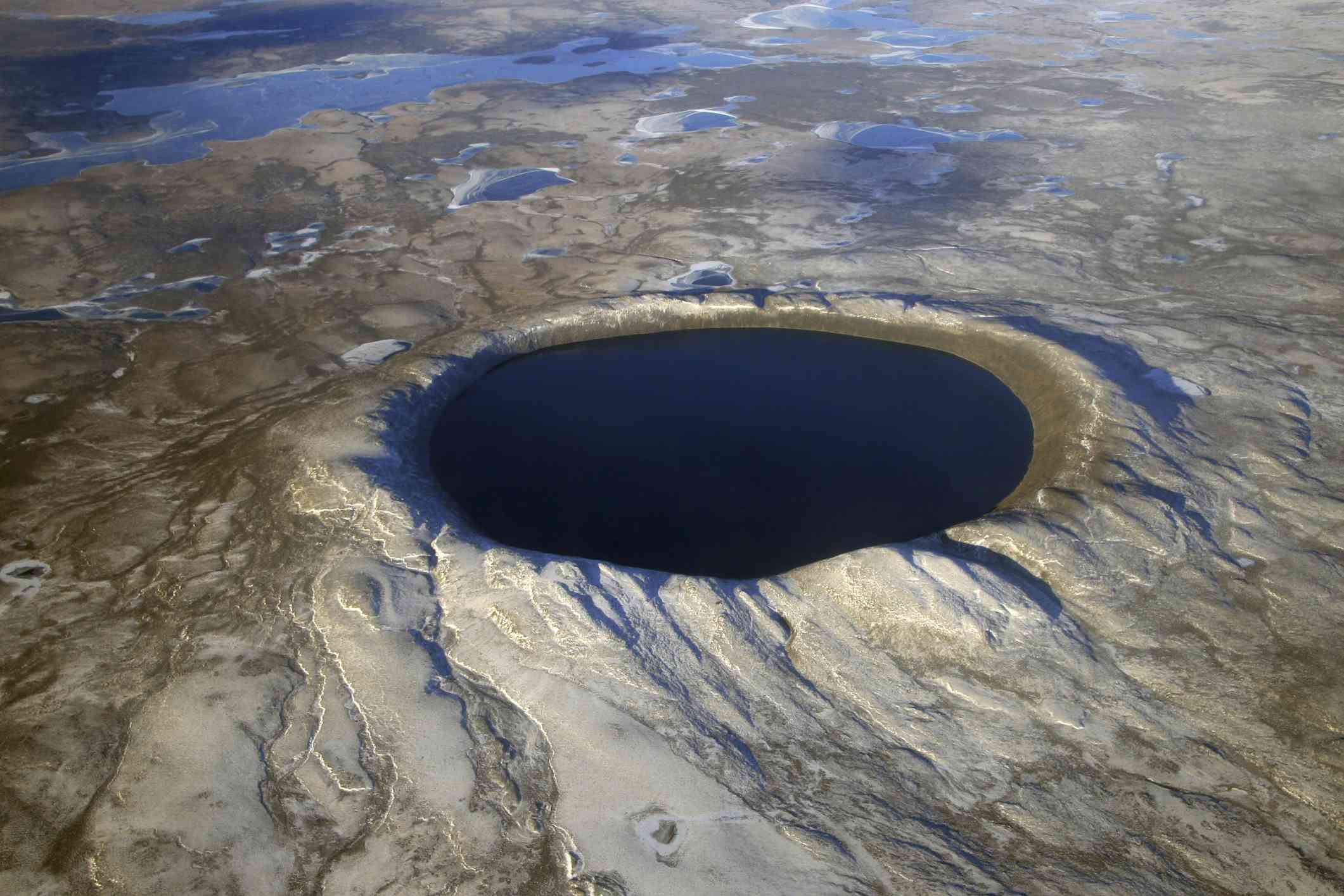 在浅褐色不平的地面上形成了黑色的小圆形陨石坑