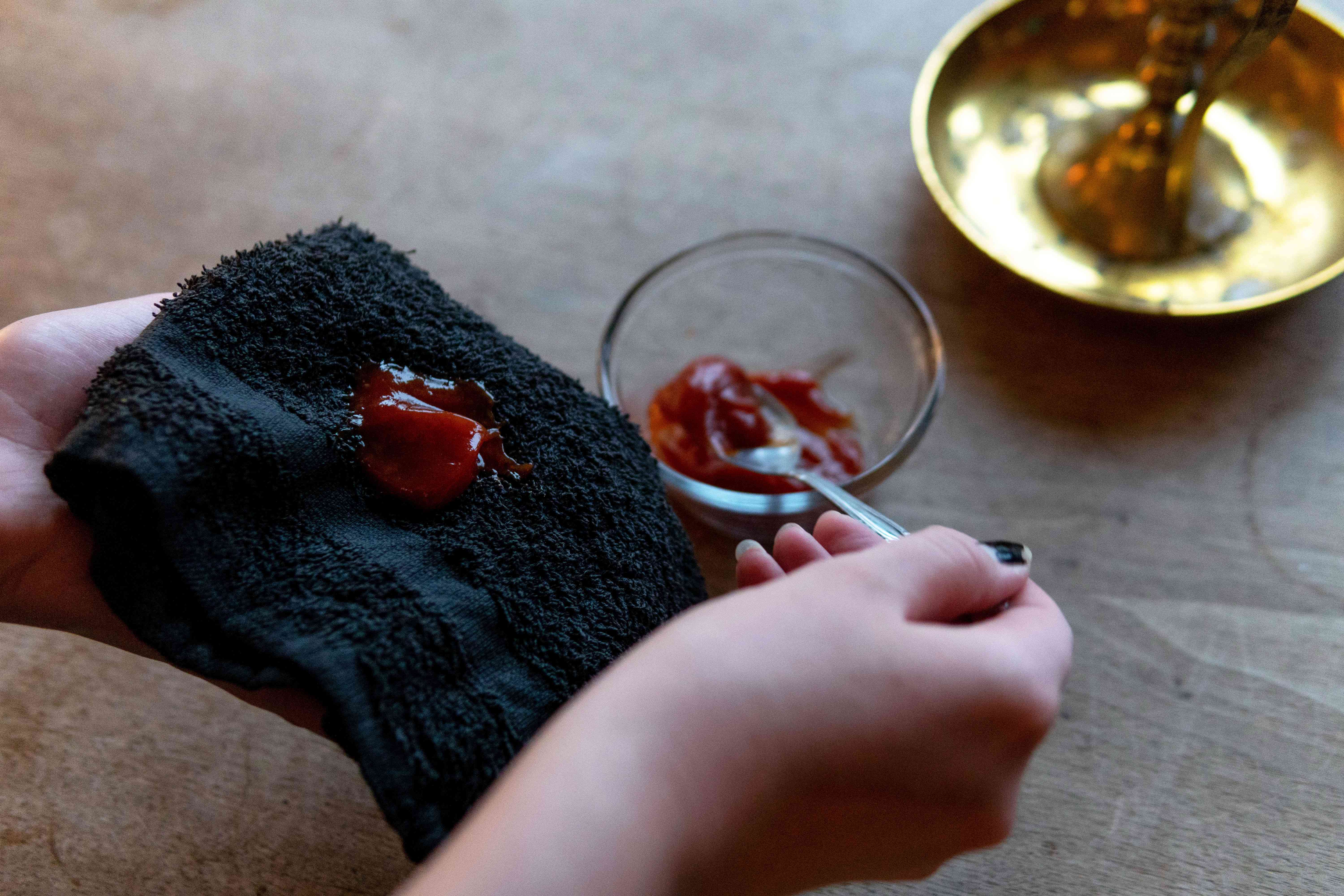 手用勺子舀番茄酱在毛巾上