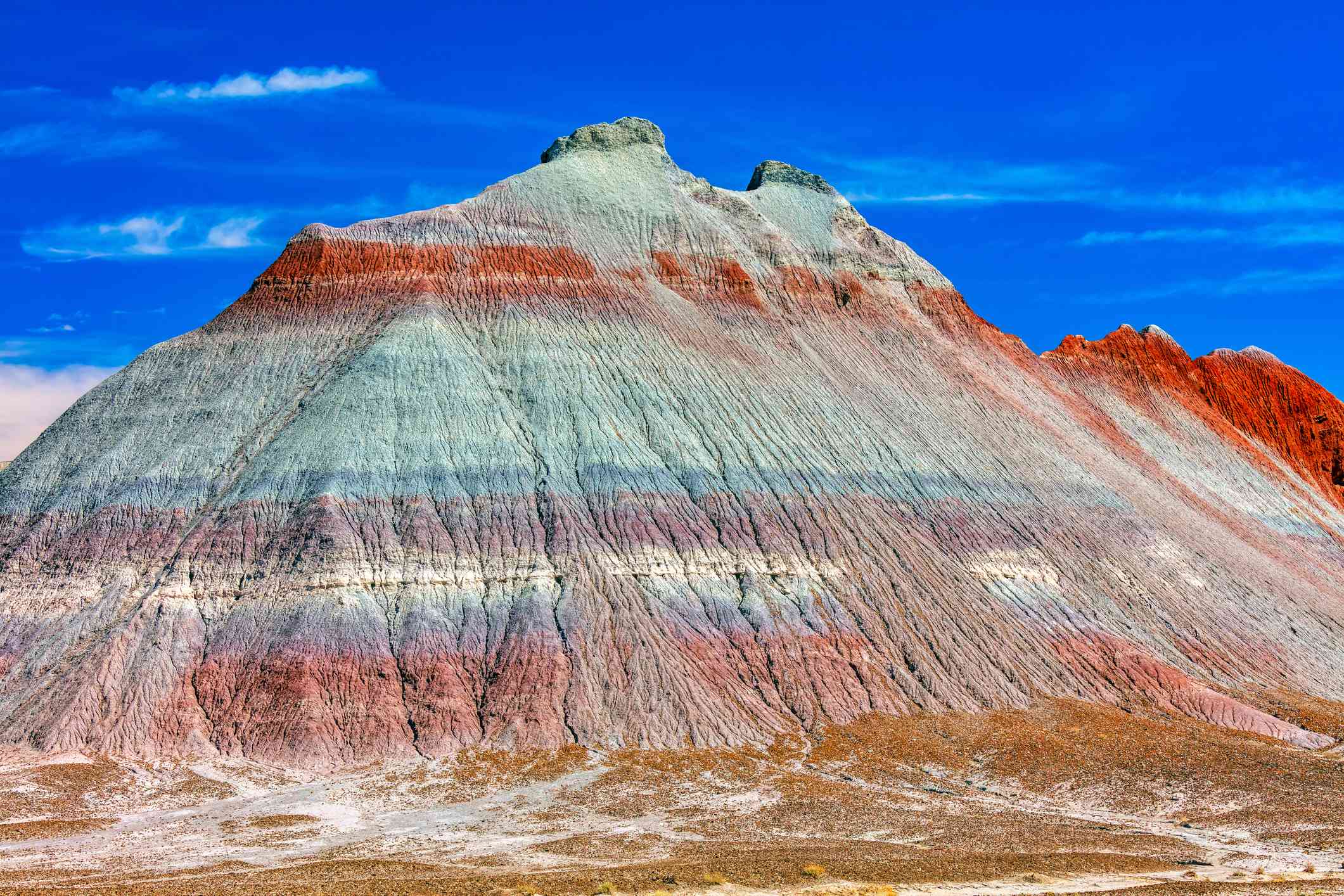 沙漠中的一座山，有红色、灰色、蓝色和紫色的石头层