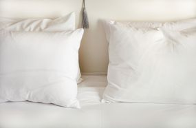 在床上的白色枕头“width=