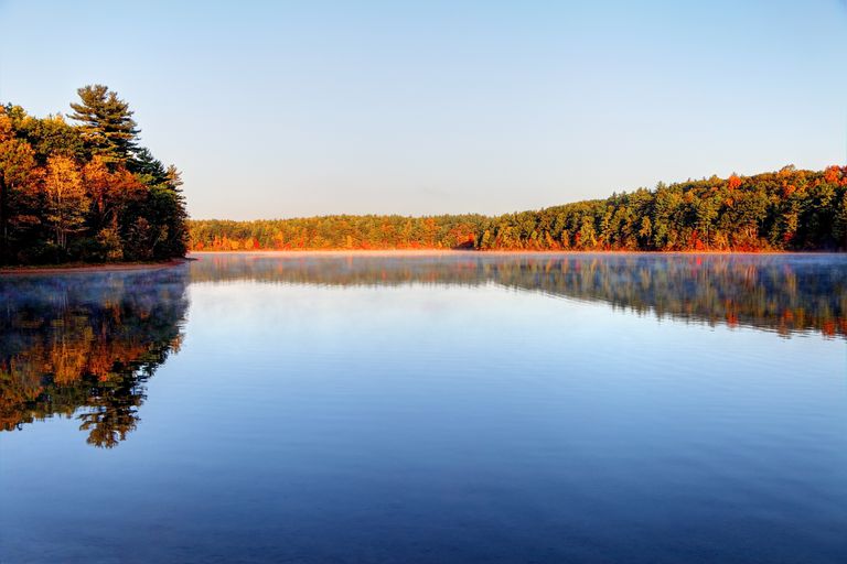 秋天的瓦尔登湖非常平坦，蓝色的水被五颜六色的树包围，上面是浅蓝色的天空