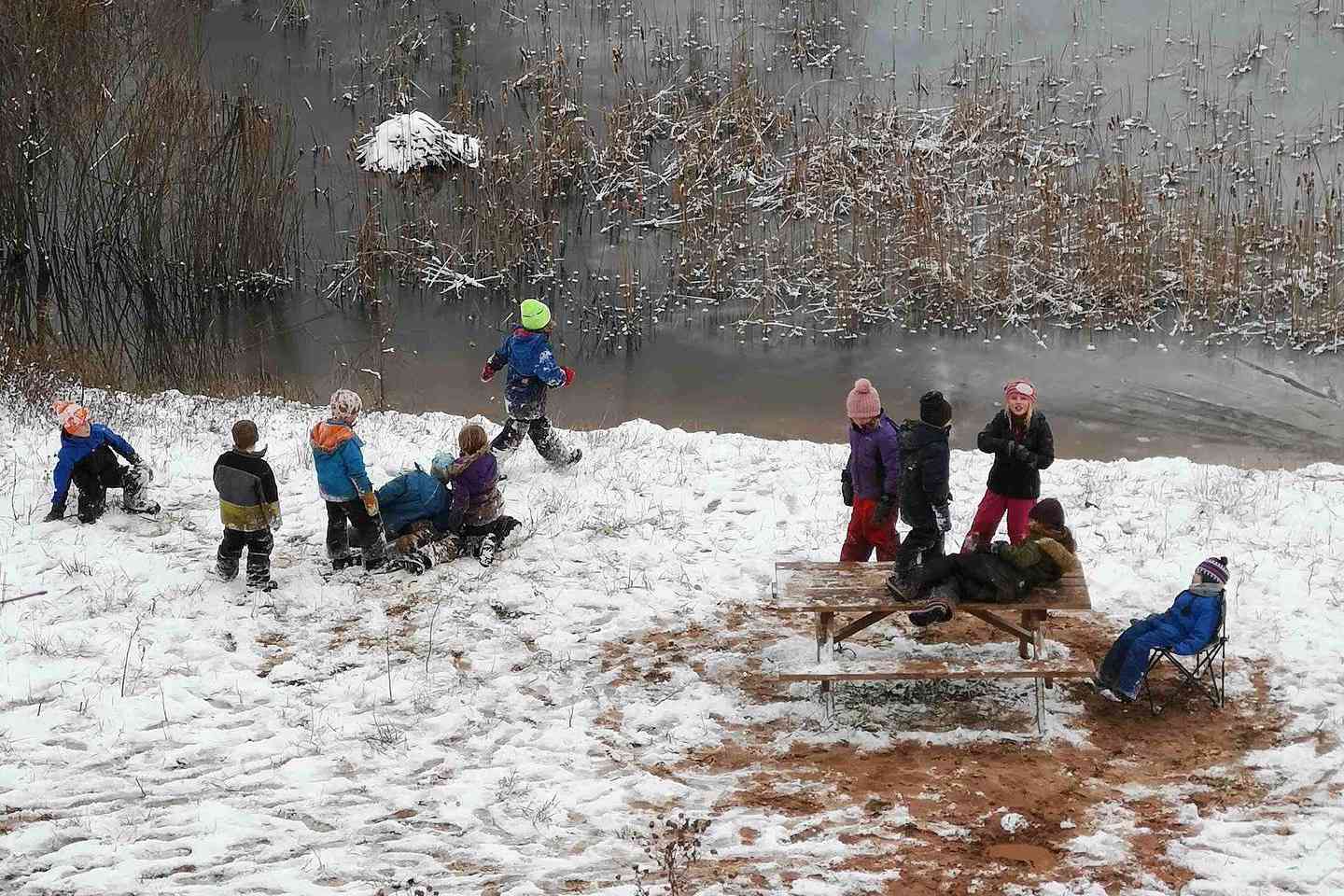 孩子站在森林学校的冷冻池塘附近