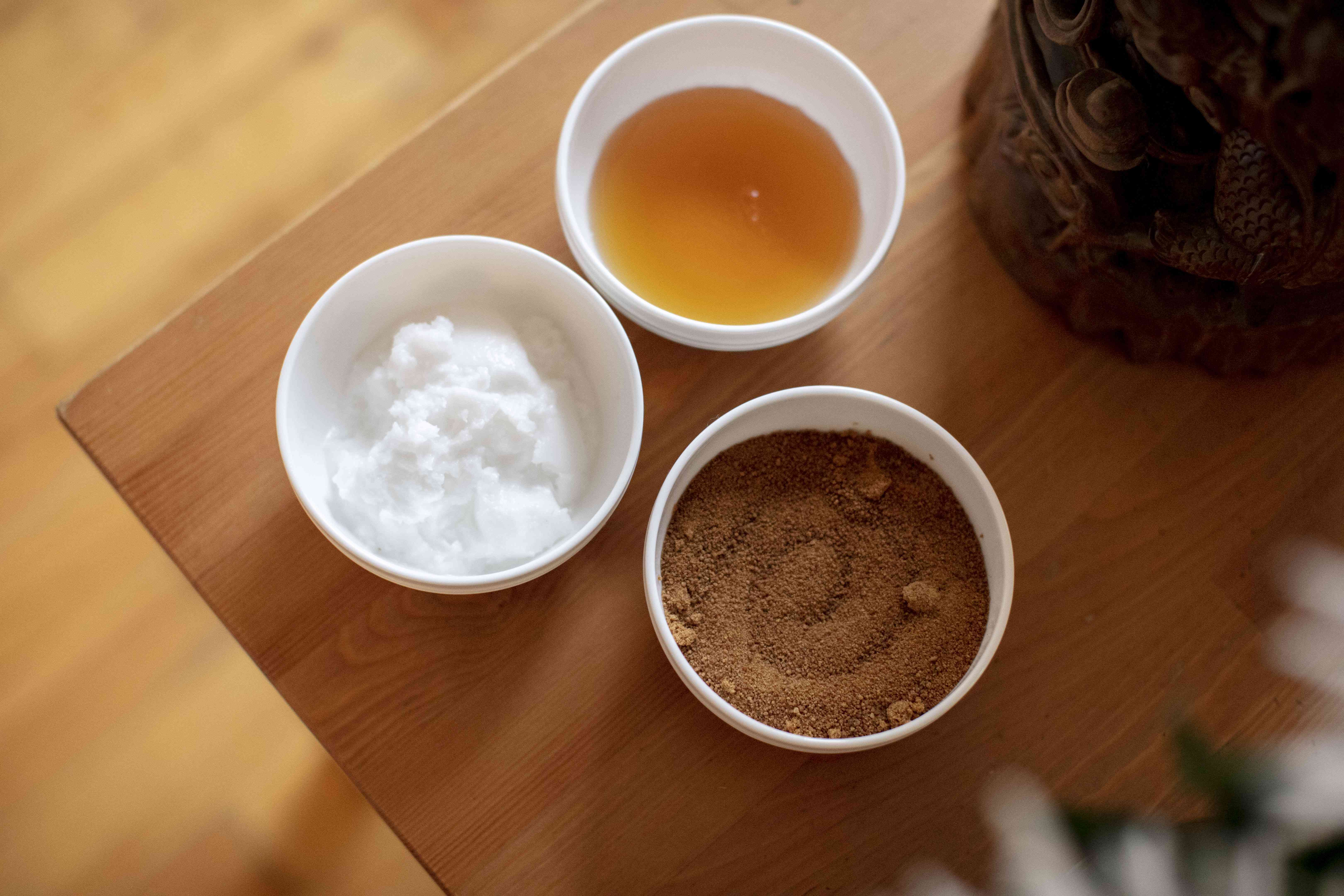 椰子糖，椰子油，蜂蜜在木制桌子上的白色陶瓷碗diy唇磨砂