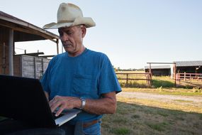 农民使用笔记本电脑的谷仓
