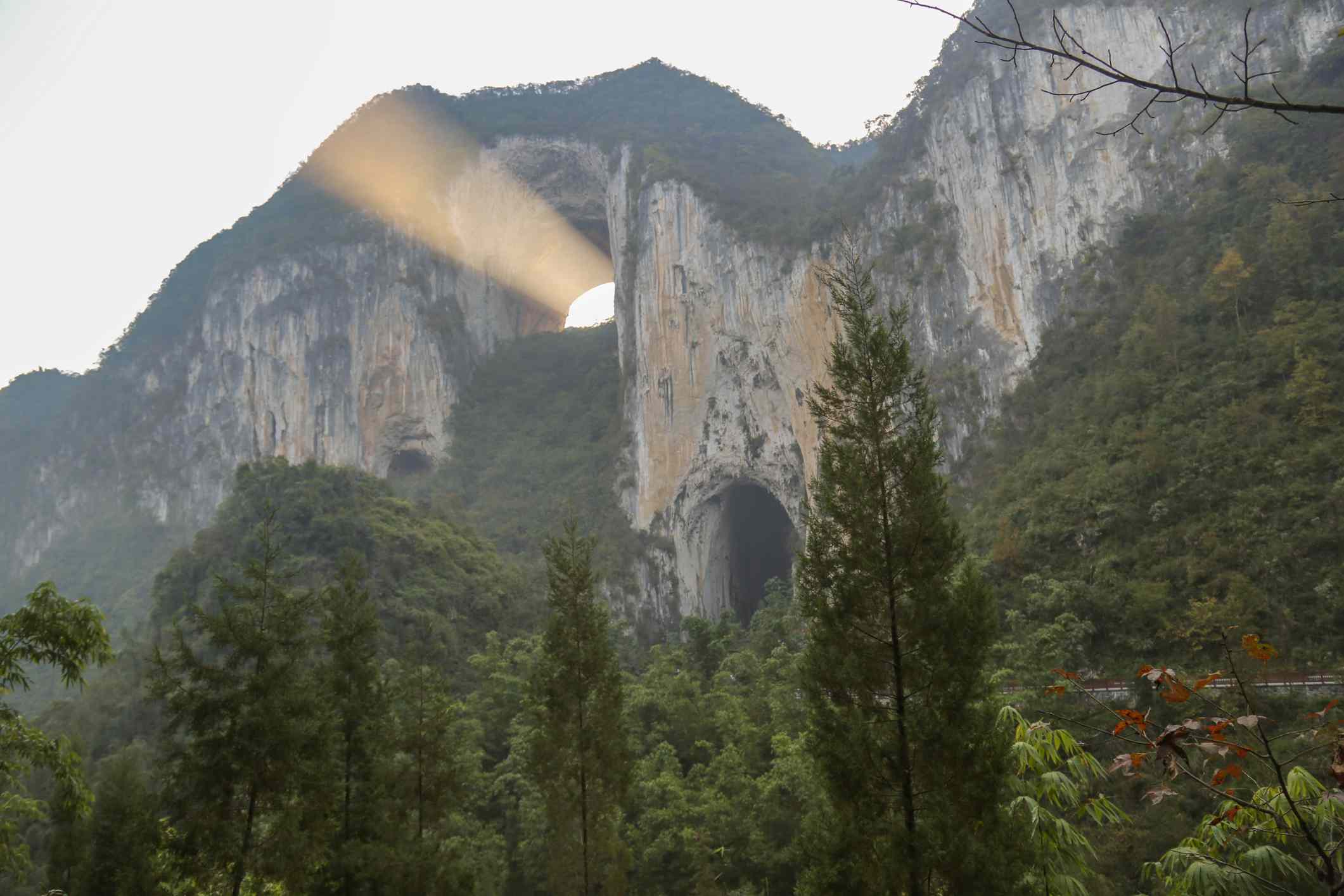 一个森林山脊，有天然拱门和一束阳光从拱门传来