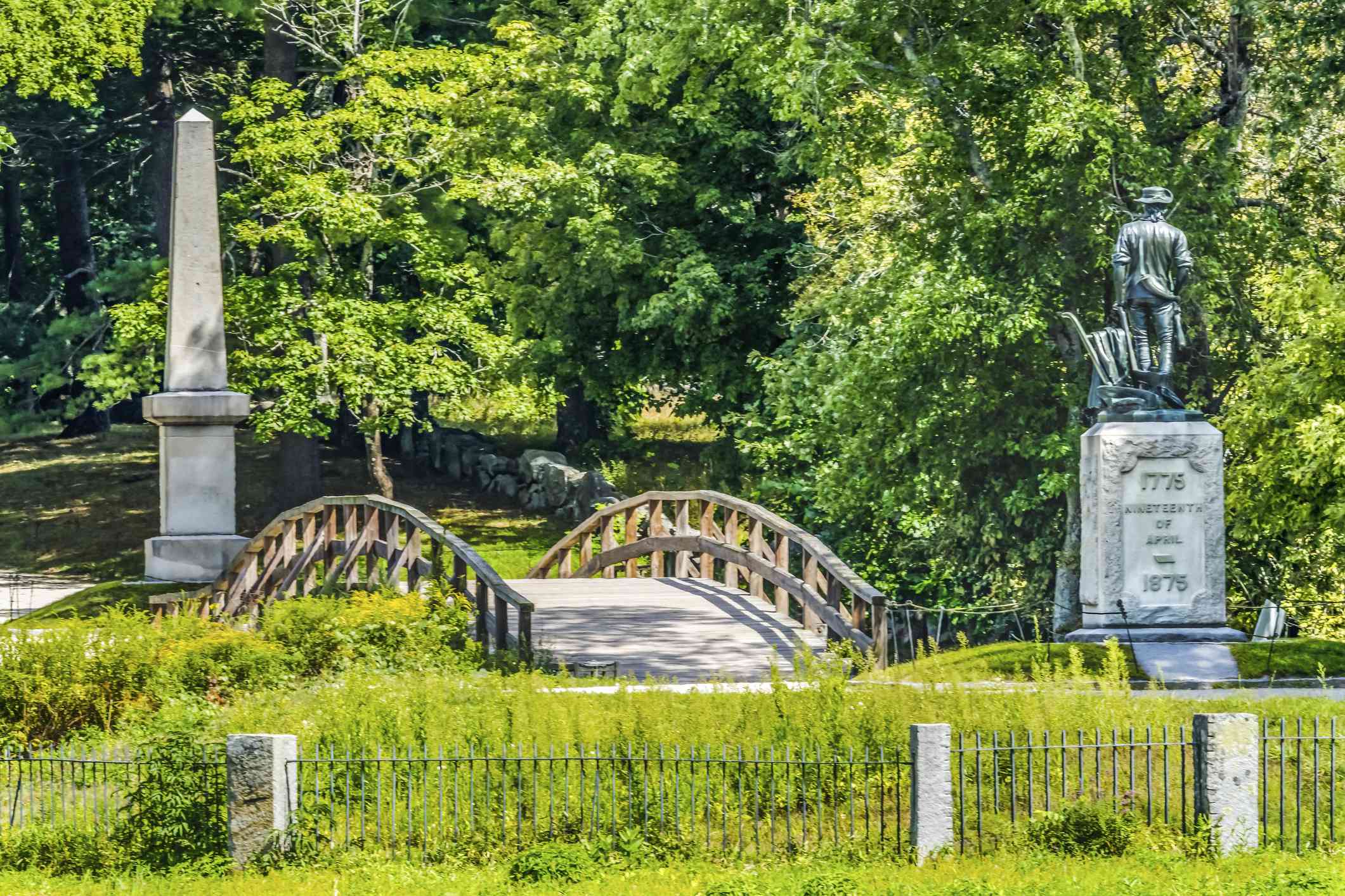 分钟人雕像旧北桥分钟人国家历史公园美国革命纪念碑马萨诸塞州第一战美国革命，1775年4月19日，周围环绕着茂密的绿树，绿树和绿色地面盖